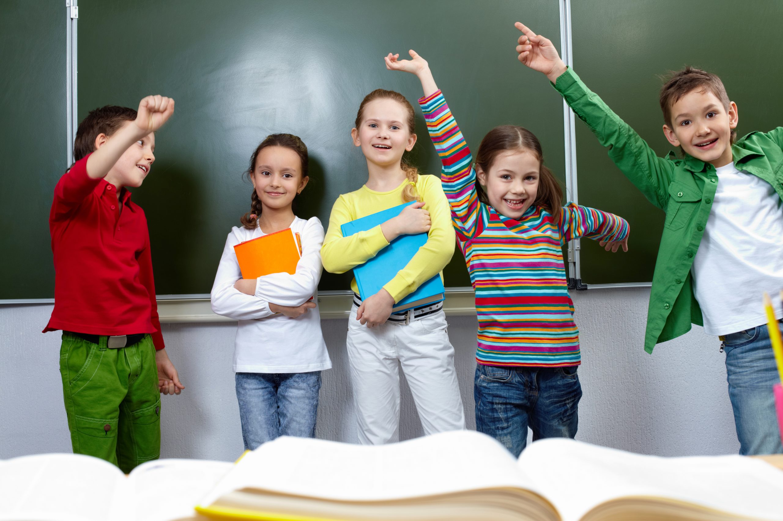 Portrait of five pupils having fun in classroom